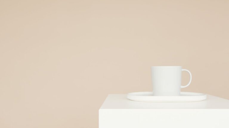 A white mug on a tray on a minimalist white block with a beige background, perfect for modern decor.