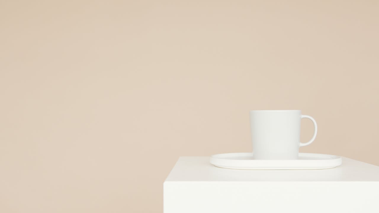 A white mug on a tray on a minimalist white block with a beige background, perfect for modern decor.